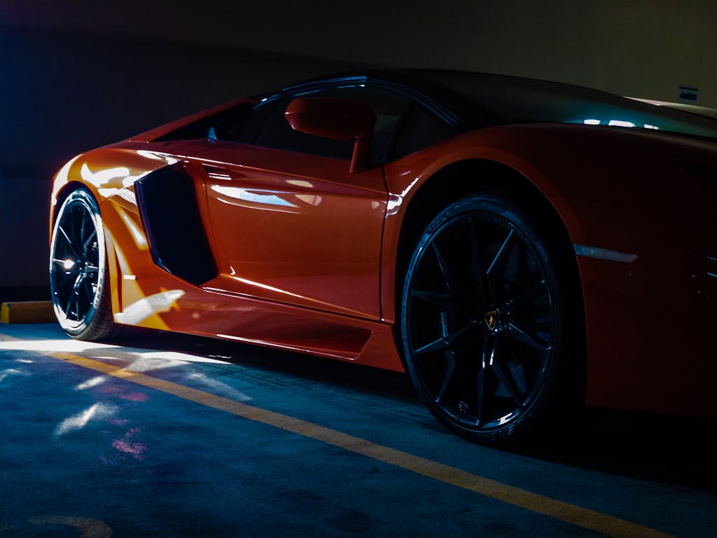 Close-up of a vibrant orange sports car parked in a sunlit garage, showcasing luxury and modern design.